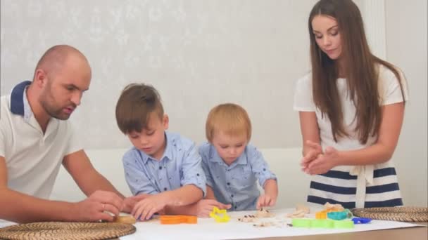 Jovens pais ensinando seus meninos como fazer biscoitos — Vídeo de Stock