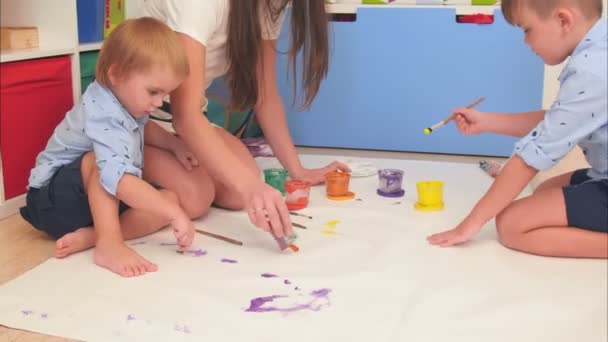 Молодая мать показывает своим маленьким сыновьям, как рисовать солнце — стоковое видео
