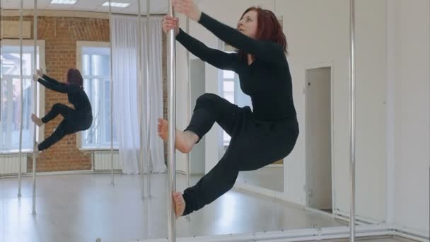 Sporty woman pole dancer makes element on pylon — Stock Video