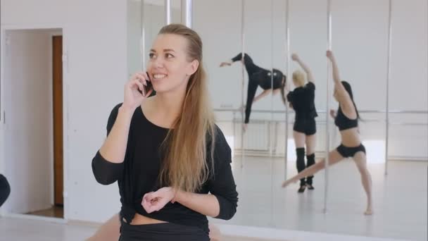 Fiatal nő van egy telefon hívás közben egy pole dance osztály — Stock videók