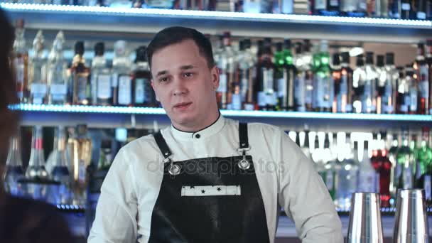 Wesoły młodych barman uśmiecha się i mówi do klienta w barze — Wideo stockowe