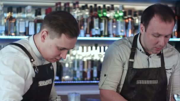 Два бармена работают и обсуждают что-то за стойкой в баре — стоковое видео