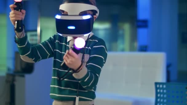 Petit garçon en réalité virtuelle casque tenant mouvement contrôleurs de mouvement — Video
