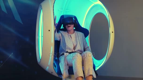 Mujer emocional que experimenta la realidad virtual en una silla interactiva en movimiento — Vídeo de stock