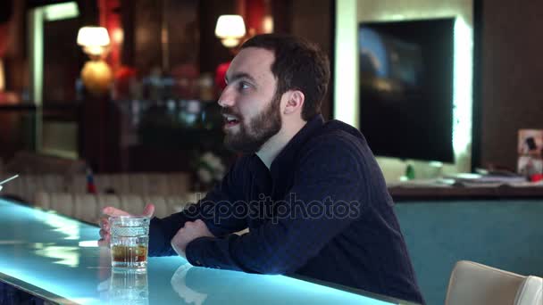 Mladý muž v baru s rozhovor s barmanem a pití — Stock video