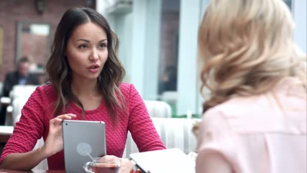 Twee vrouwen zitten in rustieke café kijken naar foto's op digitale Tablet PC — Stockvideo