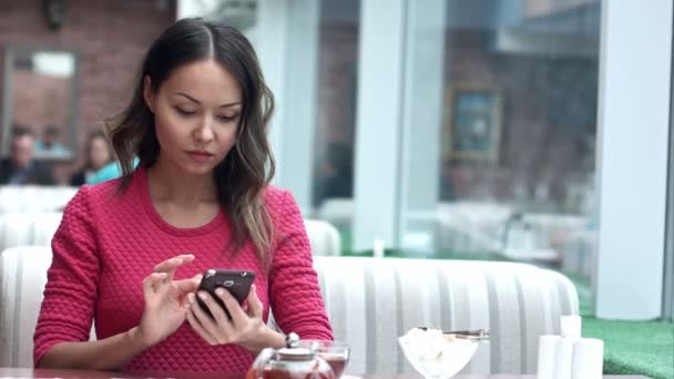Mujer asiática mirando el teléfono celular y tomando té en la cafetería — Vídeos de Stock