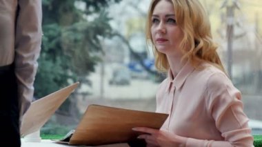 Menü kartı veren holding kafede oturan neşeli genç kadın garsona sipariş