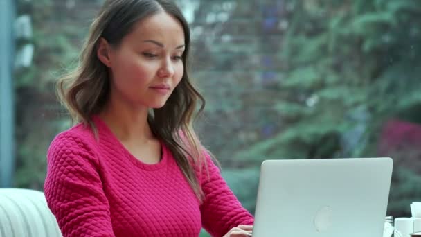 Χιλιετή νεαρή γυναίκα συνομιλία σε απευθείας σύνδεση χρησιμοποιώντας το φορητό υπολογιστή στην καφετέρια — Αρχείο Βίντεο