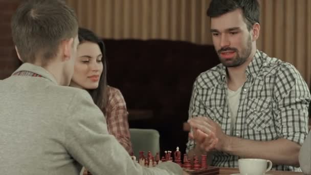 Freunde ruhen sich in einem Café aus und spielen Schach — Stockvideo