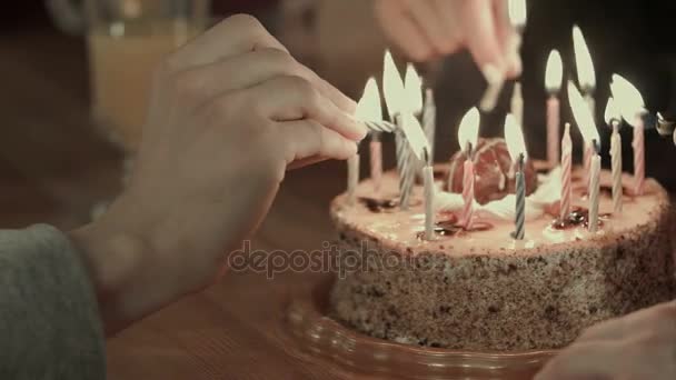 Zwei Personen zünden die Kerzen auf einer Geburtstagstorte an — Stockvideo