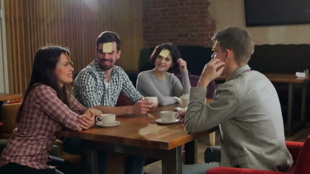 Czterech przyjaciół grają razem kim jestem w kawiarni — Wideo stockowe