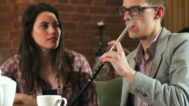 Schönes Paar raucht Wasserpfeife und redet in der Bar — Stockvideo