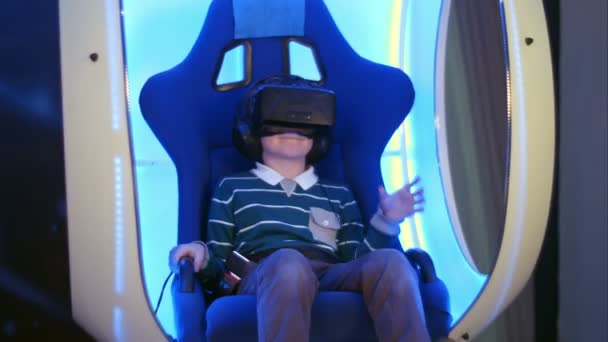 Förvånad över liten pojke uppleva virtuell verklighet i en glidande interaktiva stol — Stockvideo