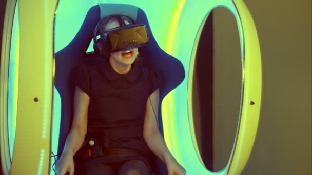 Little girl sitting in virtual reality attraction and feeling scary — Stock Video