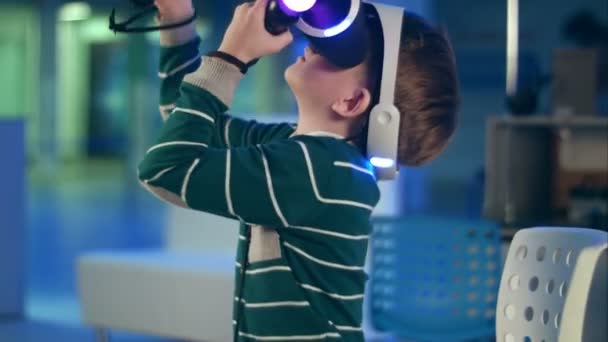 Niño activo disfrutando de la realidad virtual con controladores de movimiento en sus manos — Vídeos de Stock