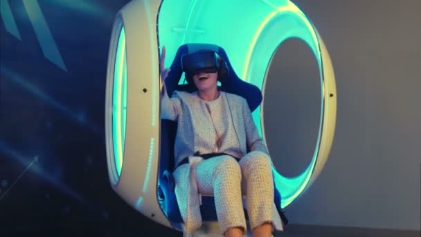 Эмоциональная женщина, переживающая виртуальную реальность в движущемся интерактивном кресле — стоковое видео