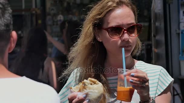 Junges Touristenmädchen isst Streetfood auf dem Stadtmarkt — Stockvideo