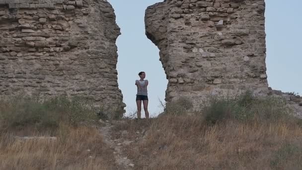 Безтурботна жінка мандрівник робить смішний танець біля стародавніх стін — стокове відео