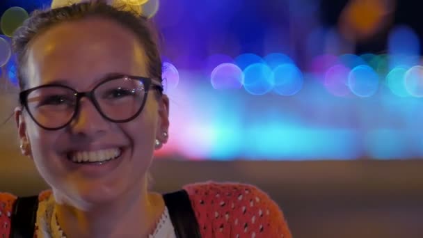 Улыбающаяся девушка в очках, наслаждающаяся ночным освещением — стоковое видео