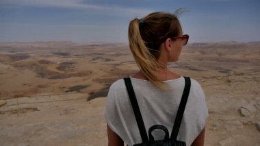 Taş zevk güneş gözlüklü genç kadın çöl uçurumun kenarında görünüm