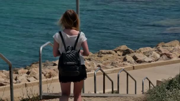 Jong meisje lopen de trap af naar de zee — Stockvideo