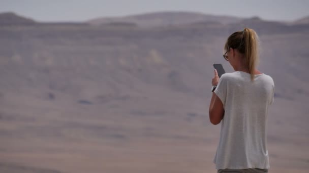 Jonge vrouw nemen van panoramische foto van de woestijn krater op haar telefoon — Stockvideo