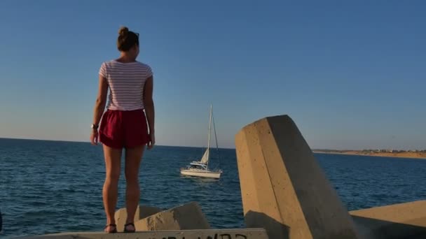 Hermosa chica en forma en pantalones cortos bailando sobre rocas grandes cerca de la orilla del mar — Vídeos de Stock