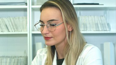 Çekici genç kadın doktor ofisinde masada oturan gözlüklü