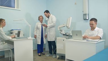 Dizüstü bilgisayarlar farklı sorular üzerinde çalışan tıbbi personel soran tablet ile genç adam