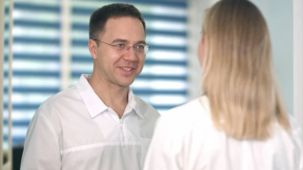 Mosolygó férfi orvos beszél a női nővér szemüveg — Stock Fotó