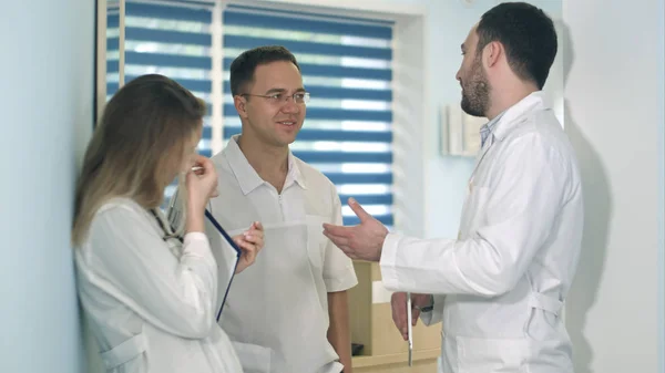 Αρσενικό ο γιατρός κρατώντας δισκίο μιλάμε για δύο άλλοι γιατροί στην αίθουσα νοσοκομείου — Φωτογραφία Αρχείου