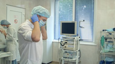 Erkek doktor hemşire bir ameliyat odasında ellerini yıkama sırasında cerrahi şapka koyarak