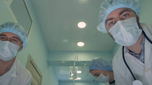 Gruppo di chirurghi che guardano il paziente mentre va in sala operatoria — Foto Stock
