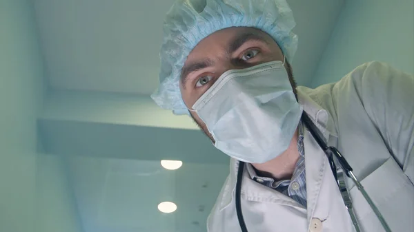 Doctor in mask looking down at patient checking his consciousness — Stock Photo, Image