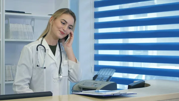 Hübsche Krankenschwester mit Tablet und Telefon an der Krankenhausrezeption — Stockfoto