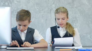 İki sevimli çocuk iş giyim iş merkezi belgeleri ve bilgisayar ile çalışma