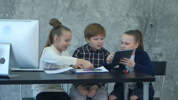 Tres niños pequeños en reuniones de negocios compartiendo ideas en la oficina, usando tabletas y documentos — Foto de Stock