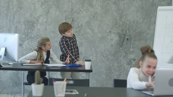 Litlle pojke drawiong på blädderblock, diskutera projektet med tjej i office — Stockfoto