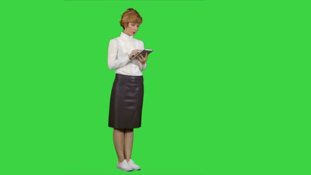 Mujer bastante joven usando la tableta en una pantalla verde, Clave de croma — Vídeos de Stock
