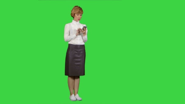 Mujer rubia bonita joven trabajando, escribiendo en el teléfono inteligente en una pantalla verde, Chroma Key — Vídeo de stock
