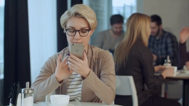 Young woman at cafe drinking coffee and using mobile phone — Stock Video