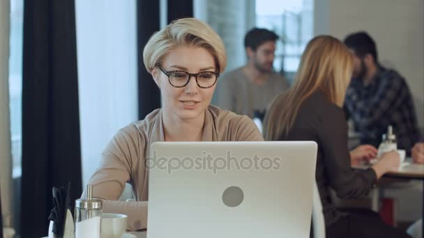 Прекрасная счастливая женщина, работающая за ноутбуком во время кофе-брейка в кафе-баре — стоковое видео