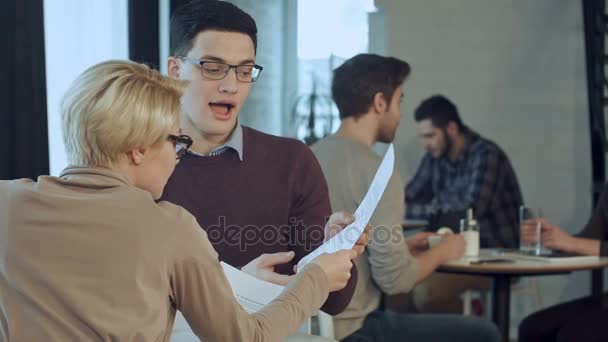 Zakelijke partners discussiëren over documenten in een café — Stockvideo