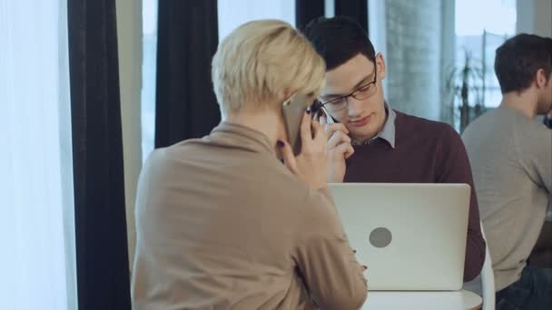 Dos compañeros de trabajo trabajando juntos, teniendo llamadas telefónicas en el café — Vídeos de Stock