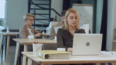 ofiste dizüstü bilgisayarda çalışan genç kadın