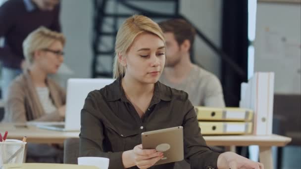 Hermosa joven en el lugar de trabajo utilizando una tableta digital — Vídeos de Stock