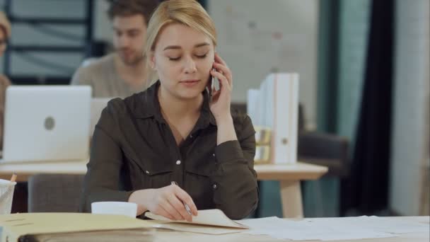 Aranyos fiatal női felnőtt, telefon, íróasztal munka közben — Stock videók