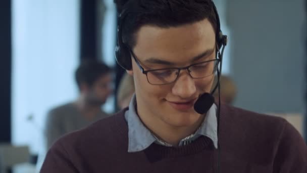 Young man working at a computer in a call centre smiling — Stock Video