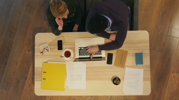 Manager en zijn mooie jonge collega zitten in kantoor en werken aan zakelijke presentatie — Stockvideo